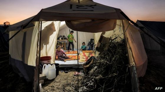 Firewood is placed at the entrance of a tent where children are sitting, at a camp housing Palestinians displaced by the conflict in Gaza between Israel and the Palestinian Hamas movement, in Rafah in the southern Gaza Strip on December 18, 2023. (Photo by Mahmud HAMS / AFP)