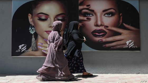 Burqa clad women walk past a billboard put up on the wall of a beauty salon in Kabul on August 7, 2021. (Photo by SAJJAD HUSSAIN / AFP)