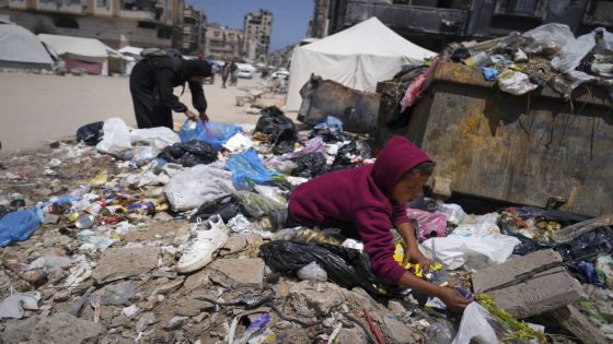 Islam Abu Taeima, a 40-year-old mother of five, left, and a boy look for some food on a pile of garbage in Gaza City, Sunday, May 25, 2025.(AP Photo/Jehad Alshrafi)
