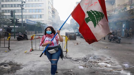 FILE PHOTO: A demonstrator carries a national flag along a blocked road, during a protest against the fall in Lebanese pound currency and mounting economic hardships, near the Central Bank building, in Beirut, Lebanon March 16, 2021. REUTERS/Mohamed Azakir/File Photo