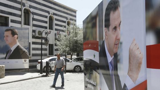 A Syrian man walks walks in between election campaign posters bearing portraits of Syrian President Bashar al-Assad, a candidate for the upcoming presidential election, in the capital Damascus on May 18, 2021. - A Syrian former minister and a member of the Damascus-tolerated opposition will face Bashar al-Assad in the May 26 presidential election, the constitutional court said. (Photo by LOUAI BESHARA / AFP)