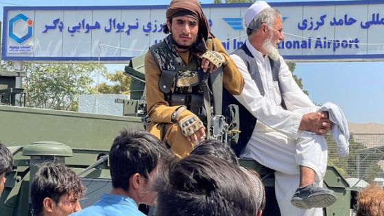 A member of Taliban forces (L) sits on a an armoured vehicle outside Hamid Karzai International Airport in Kabul, Afghanistan August 16, 2021. REUTERS/Stringer NO RESALES. NO ARCHIVES