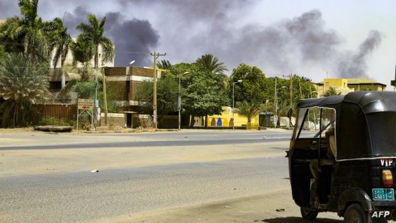 Smoke rises from buildings as a tuktuk taxi driver sits in his vehicle along a deserted street in Khartoum on April 16, 2023, during ongoing fighting between the forces of 2 rival generals. - Violence erupted early on April 15 after weeks of deepening tensions between army chief Abdel Fattah al-Burhan and his deputy, Mohamed Hamdan Daglo, commander of the heavily-armed paramilitary Rapid Support Forces (RSF), with each accusing the other of starting the fight. (Photo by AFP)