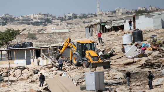 Israeli police secure a bulldozer demolishing structures at the Bedouin village of Abu Nuwar, near Abu Dis, east of Jerusalem in the occupied West Bank on July 4, 2018. Israel carried out a series of demolitions Wednesday on what it described as illegally built structures. Photo by Shadi Hatem