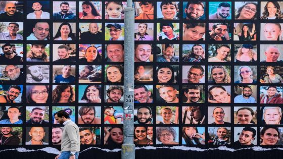 A man walks past a giant billboard featuring portraits of Israeli hostages held in Gaza since the October 7 attack by Hamas militants, in Jerusalem as a truce between Israel and Hamas entered its second day on November 25, 2023. Hamas is expected to release another 14 Israeli hostages in exchange for 42 Palestinian prisoners on November 25, as part of a four-day truce in their seven-week war. (Photo by John MACDOUGALL / AFP)