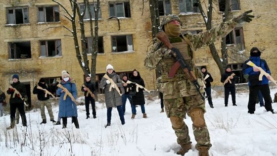 TOPSHOT - A military instructor teaches civilians holding wooden replicas of Kalashnikov rifles, during a training session at an abandoned factory in the Ukrainian capital of Kyiv on January 30, 2022. - As fears grow of a potential invasion by Russian troops massed on Ukraine's border, within the framework of the training there were classes on tactics, paramedics, training on the obstacle course. The training is conducted by instructors with combat experience, members of the public initiative "Total Resistance". (Photo by Sergei SUPINSKY / AFP) (Photo by SERGEI SUPINSKY/AFP via Getty Images)