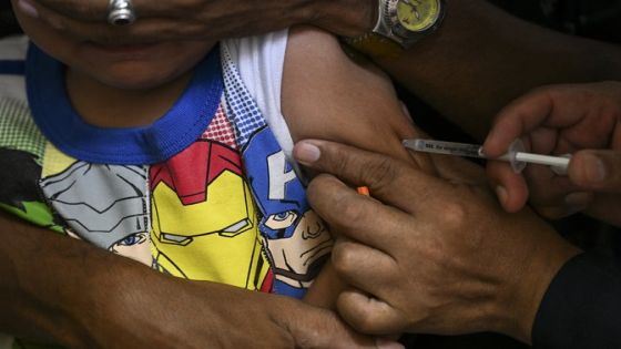 A boy accompanied by his father receives a dose of the measles and rubella vaccine from medical personnel at a community health center in the Lidice neighborhood of Caracas, on August 17, 2022. - The government maintains a massive vaccination campaign that began last June, aiming to vaccinate the child population and administer reinforcements against polio, measles, rubella, yellow fever, rotavirus, COVID-19, and others. (Photo by Yuri CORTEZ / AFP)