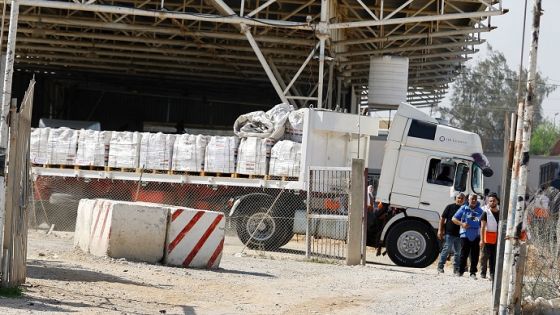 A UN worker and other workers stand next to an aid truck at Rafah crossing, as the conflict between Israel and Palestinian Islamist group Hamas continues, in the southern Gaza Strip October 21, 2023. REUTERS/Ibraheem Abu Mustafa