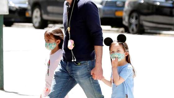 A man holds the hands of two young girls wearing masks as they cross the street as residents of New York City adjust to living with the ongoing outbreak of the coronavirus disease (COVID-19) in the Manhattan borough of New York U.S., May 20, 2020. REUTERS/Lucas Jackson