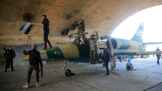 An anti-government fighters celebrate around a Syrian regime military aircraft at the Kuweires military airfield in the eastern part of Aleppo province on December 1, 2024. Syria's second-largest city Aleppo has fallen from government control for the first time since the country's conflict began more than a decade ago, a war monitor said on December 1, after a surprise advance by rebels. (Photo by Aref TAMMAWI / AFP)