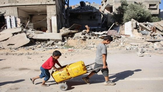Palestinian boys transport water containers past buildings destroyed during previous Israeli bombardment, in Gaza City on June 10, 2024, amid the ongoing conflict between Israel and the Palestinian Hamas militant group. (Photo by Omar AL-QATTAA / AFP)