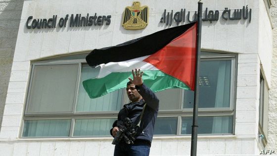 A member of the Al-Aqsa Martyrs Brigades, loyal to the former ruling Fatah faction and Palestinian Authority president Mahmud Abbas, stands outside the Council of Ministers in the West Bank town of Ramallah 13 April 2006. Masked gunmen from the Al-Aqsa Martyrs Brigades briefly occupied the Palestinian prime minister's West Bank offices to demand benefits from the cash-strapped Hamas government. Around two dozen militants forced their way into the downtown building in the middle of a video-conference linking senior civil servants based in the West Bank town with their counterparts in Gaza City, while storming the transport ministry at the same time, security sources and witnesses told AFP. One of the ringleaders said the protest was staged to demand the restoration of recently revoked benefits, including permits which enable the families of people killed in the ongoing Palestinian uprising to travel free by taxi. AFP PHOTO/JAMAL ARURI (Photo by JAMAL ARURI / AFP)