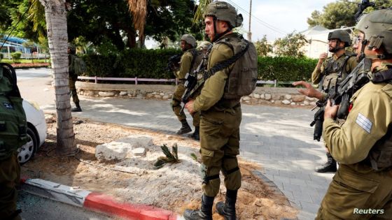 Israeli soldiers stand near a vehicle with the dead body of a man who was killed following a mass-infiltration by Hamas gunmen from the Gaza Strip, in Sderot, southern Israel October 7, 2023. REUTERS/Ammar Awad