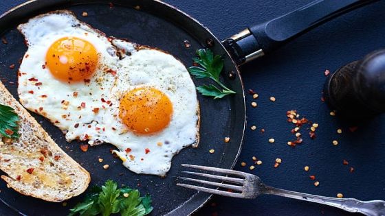 Fried eggs and slice of bread on pan