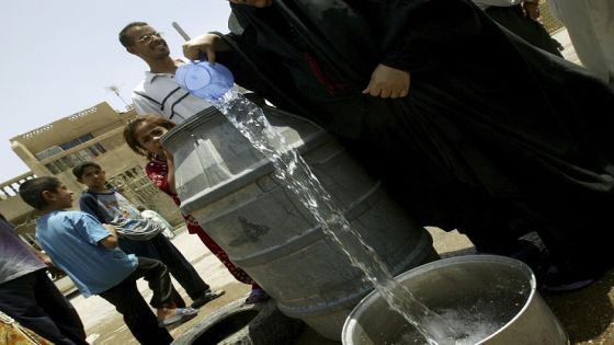 BAGHDAD, IRAQ - JULY 01: An Iraqi women gets water from a barrelas after a fire at a power station has left left millions without drinking water on July 1, 2005 in Baghdad, Iraq. Baghdad's mayor decried the capital's crumbling infrastructure and the lack of clean water and threatened to resign if the Iraqi government won't provide more money. (Photo by Ghaith Abdul-Ahad/Getty Images)