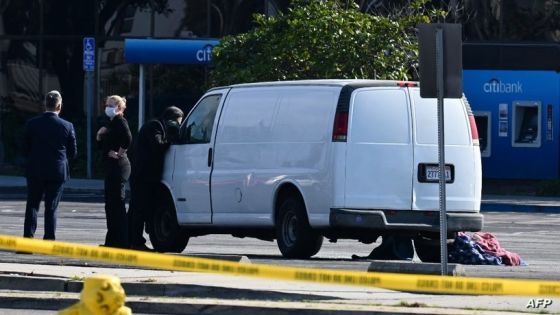 A law enforcement official looks into the window of a van with a body in the driver's seat in Torrance, California, on January 22, 2023. - California police hunting the gunman who killed 10 people at a dance club during Lunar New Year celebrations broke into a van after a lengthy standoff Sunday, where images showed a body slumped in the driver's seat. The hunt began 12 hours earlier after a man -- described by police as Asian -- began firing at a club in Monterey Park, a city in Los Angeles County with a large Asian community. (Photo by Robyn BECK / AFP)