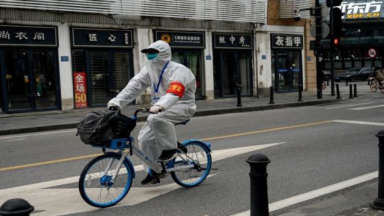 A man wearing a protective suit as a preventive measure against the COVID-19 coronavirus rides a bike along a street in Wuhan in China's central Hubei province on March 31, 2020. (Photo by NOEL CELIS / AFP)