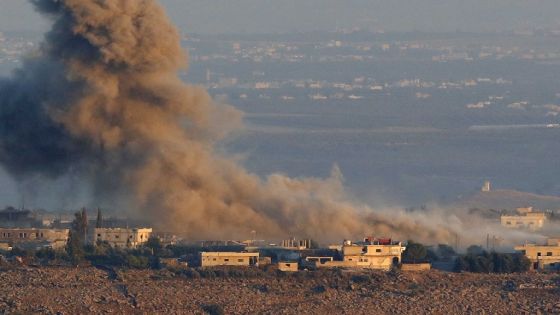 A picture taken on July 26, 2018, near the Ein Zivan settlement in the Israeli-annexed Golan Heights, shows smoke rising above buildings across the border in Syria during air strikes backing a government-led offensive in the southern province of Quneitra. - Syrian government forces raised the country's two-star flag on the frontier with the Israeli-occupied Golan Heights on Thursday, the Syrian Observatory for Human Rights said, four years since they were last deployed there. (Photo by Jack GUEZ / AFP)