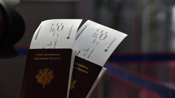 Passengers hold their passports with Air France travel documents with the 'ready to fly' health documentation at Roissy Charles de Gaulle Airport, north of Paris on July 20, 2021. (Photo by Eric PIERMONT / AFP)