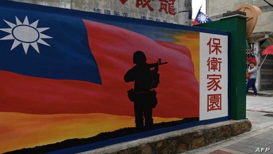 This photo taken on October 21, 2020 shows a tourist (R) walking past a mural painted on a wall on Taiwan's Kinmen islands, which lie just 3.2 kms (two miles) from the mainland China coast (in background) in the Taiwan Strait. - The tank traps on the beaches of Kinmen Island are a stark reminder that Taiwan lives under the constant threat of a Chinese invasion -- and fears of a conflict breaking out are now at their highest in decades. (Photo by Sam Yeh / AFP) / TO GO WITH Taiwan-China-US-politics-military-Kinmen,FOCUS by Amber WANG and Jerome TAYLOR