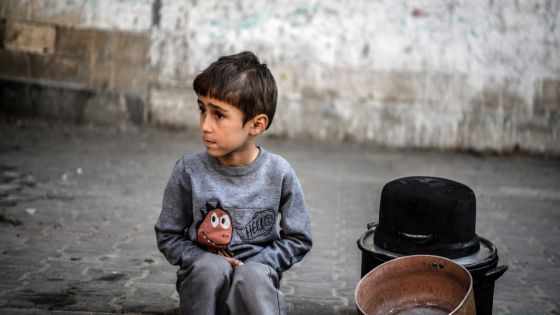 حول ثلاثة أقدار من الأرز وطبيخ "الفاصولياء" الساخن، يتزاحم عشرات النازحين الفلسطينيين وأصحاب المنازل المدمرة بفعل الحرب الإسرائيلية، للحصول على الوجبات المجانية لسد رمق عائلاتهم التي لا تجد في الكثير من الأحيان هذا النوع من الطعام. يمد هؤلاء الأشخاص المتواجدون في مخيم الشابورة للاجئين الفلسطينيين وسط مدينة رفح جنوبي القطاع، الأواني البلاستيكية والحديدية للفلسطيني خالد بركات، الذي يعتلي طاولة خشبية وضع عليها الأقدار. وباستخدام وعاء حديدي كبير، يبدأ الفلسطيني خالد بركات، صاحب المبادرة الفردية التطوعية لتوزيع الوجبات المجانية، بسكب الطبيخ داخل أواني النازحين، الذين يكون بينهم عدد كبير من النساء والأطفال. ( Abed Zagout - وكالة الأناضول )