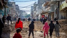 Children and adults walk through a devastated street in Tulkarem city, West Bank on January 09, 2025, following the withdrawal of the Israeli army from the Nur Shams and Tulkarem refugee camps. Military bulldozers tore through the roads, leaving infrastructure in ruins and homes severely damaged. (Photo by Wahaj Bani Moufleh / Middle East Images / Middle East Images via AFP)