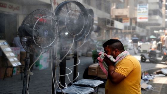 A man stands by fans spraying air mixed with water vapour deployed by donors to cool down pedestrians along a street in Iraq's capital Baghdad on June 30, 2021 amidst a severe heat wave. (Photo by AHMAD AL-RUBAYE / AFP)