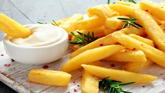 Homemade Baked Potato Fries with Mayonnaise and rosemary on white wooden board.