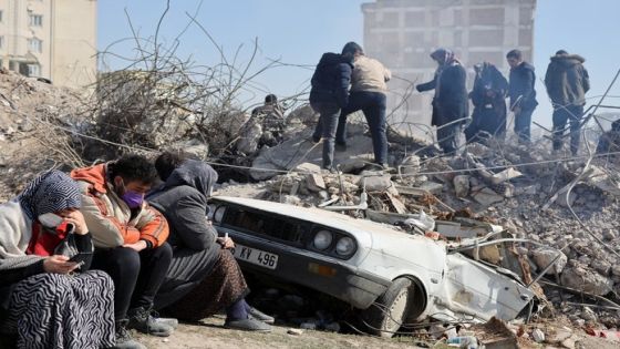 People sit as others search amid the rubble in the aftermath of a deadly earthquake in Kahramanmaras, Turkey February 14, 2023. REUTERS/Nir Elias