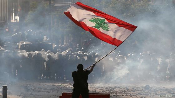 FILE PHOTO: A demonstrator waves the Lebanese flag in front of riot police during a protest in Beirut, Lebanon, August 8, 2020. REUTERS/Goran Tomasevic/File Photo
