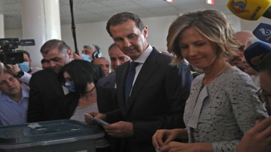 Syrian President Bashar al-Assad (C) and his wife Asma (R) cast their votes at a polling station in Douma, near Damascus on May 26, 2021, as voting began across Syria for an election guaranteed to return Assad for a fourth term in office. - The 55-year-old president, who has been in power since 2000, is sure to keep his job after the election, every aspect of which is controlled by him and his Baath party. He faces former state minister Abdallah Salloum Abdallah and Mahmoud Merhi, a member of the so-called "tolerated opposition", long described by exiled opposition leaders as an extension of the regime. (Photo by LOUAI BESHARA / AFP)