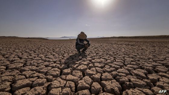 A child crouches over cracked earth at al-Massira dam in Ouled Essi Masseoud village, some 140 kilometres (85 miles) south from Morocco's economic capital Casablanca, on August 8, 2022 amidst the country's worst drought in at least four decades. - Residents of Morocco's Ouled Essi Masseoud village are suffering from a series of successive droughts, prompting them to rely solely on sporadic supplies in public fountains and from private wells. The situation is critical, given the village's position in the agricultural province of Settat, near the Oum Errabia river and al-Massira dam, Morocco's second largest. Its reservoir supplies drinking water to several cities, including the three million people who live in Casablanca. But latest official figures show it is now filling at a rate of just five percent. (Photo by FADEL SENNA / AFP)