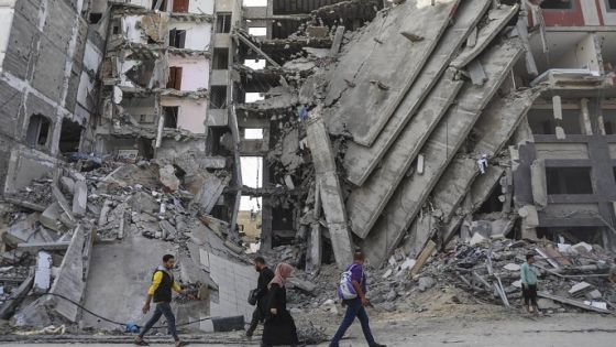 Palestinians walk through destruction in Gaza City on Friday, Nov. 24, 2023, as the temporary ceasefire between Israel and Hamas took effect. (AP Photo/Mohammed Hajjar)