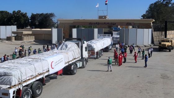 People on the Egyptian side of the Rafah border crossing watch as a convoy of lorries carrying humanitarian aid crosses to the Gaza Strip on October 21, 2023. The first of 20 trucks carrying humanitarian aid entered the war-torn and besieged Gaza Strip on October 21 through the Rafah border crossing with Egypt, said AFP correspondents on both sides. (Photo by Mohammed Assad / AFP)