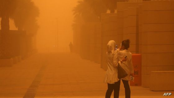 Women film with their phones amidst a severe dust storm in Kuwait City on May 23, 2022. (Photo by Yasser Al-Zayyat / AFP)