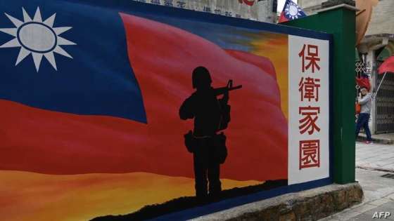 This photo taken on October 21, 2020 shows a tourist (R) walking past a mural painted on a wall on Taiwan's Kinmen islands, which lie just 3.2 kms (two miles) from the mainland China coast (in background) in the Taiwan Strait. - The tank traps on the beaches of Kinmen Island are a stark reminder that Taiwan lives under the constant threat of a Chinese invasion -- and fears of a conflict breaking out are now at their highest in decades. (Photo by Sam Yeh / AFP) / TO GO WITH Taiwan-China-US-politics-military-Kinmen,FOCUS by Amber WANG and Jerome TAYLOR