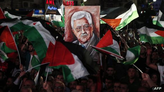 Palestinians wave their national flags and a portrait of their president Mahmud Abbas as they watch a live-screening of his speech followed by the raising of the Palestinian flag at the United Nations headquarters in New York, on September 30, 2015 in the city of Ramallah. Earlier in the week the UN General Assembly, by a two-thirds vote, adopted a resolution allowing the flags of Palestine and the Holy See -- both of which have non-member observer status -- to be hoisted alongside those of member states. AFP PHOTO / ABBAS MOMANI (Photo by Abbas MOMANI / AFP)
