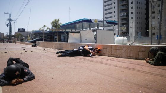 Israeli security personnel take cover as sirens sound warning of incoming rockets launched from the Gaza Strip, in Ashkelon, southern Israel May 11, 2021. REUTERS/Nir Elias