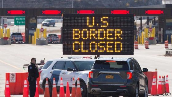 (FILES) In this file photo taken on March 22, 2020 US Customs officers speaks with people in a car beside a sign saying that the US border is closed at the US/Canada border in Lansdowne, Ontario. - Canada's border with the United States will remain closed to all non-essential travelers until March 21, Public Safety Minister Bill Blair announced February 19, 2021. (Photo by Lars Hagberg / AFP)