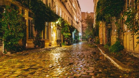 Paris, France - April 10, 2016: Beautiful old street in Paris with retro old brick road classical buildings and night lighting.