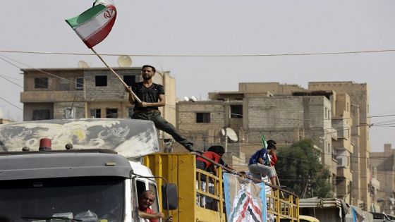 A Syrian man holds the Iranian flag as a convoy carrying aid provided by Iran arrives in the eastern city of Deir Ezzor on September 20, 2017 while Syrian government forces continue to press forward with Russian air cover in the offensive against Islamic State group jihadists across the province.
Two separate offensives are under way against the jihadists in the area -- one by the US-backed Syrian Democratic Forces, the other by Russian-backed government forces. The Syrian army now controls around 70 percent of the city and is battling to oust IS from the remainder, according to the Britain-based Observatory. / AFP PHOTO / LOUAI BESHARA (Photo credit should read LOUAI BESHARA/AFP via Getty Images)