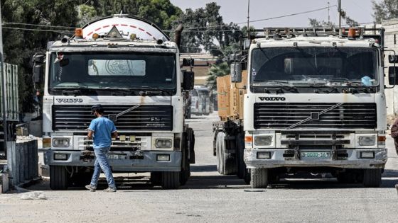 Palestinian workers walk by parked freight trucks at the Kerem Shalom commercial border crossing in Rafah in the southern Gaza Strip on September 5, 2023. Israel's army chief on September 4 ordered the suspension of all imports from Gaza after an alleged attempt to smuggle explosives, the army and defence ministry said in a statement. (Photo by SAID KHATIB / AFP)