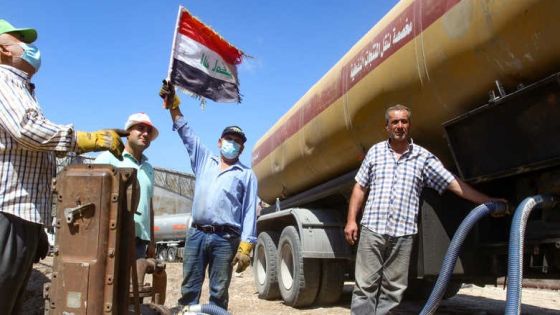 A man raises an Iraqi national flag as a tanker truck filled with fuel offered by Iraq empties its content at the oil refinery of Zahrani, near the southerm Lebanese city of Sidon (Saida) on August 20, 2020. (Photo by Mahmoud ZAYYAT / AFP)