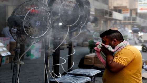 A man stands by fans spraying air mixed with water vapour deployed by donors to cool down pedestrians along a street in Iraq's capital Baghdad on June 30, 2021 amidst a severe heat wave. (Photo by AHMAD AL-RUBAYE / AFP)