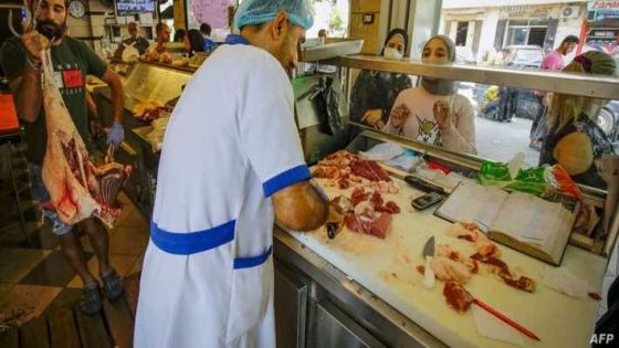 (FILES) This file photo taken on July 28, 2020 shows people waiting for their orders at a butcher in Lebanon's northern port city of Tripoli, as Muslims across the world are getting ready to celebrate Eid al-Adha. - Lebanon is grappling with an unprecedented financial crisis that the World Bank says is of a scale usually associated with fullscale wars. The currency has lost more than 90 percent of its value on the black market, more than 80 percent of the population lives in poverty, and prices have skyrocketed. The price of imported red meat has increased five fold, with some cuts costing more than the monthly minimum wage of 675,000 Lebanese pounds ($33). (Photo by IBRAHIM CHALHOUB / AFP)