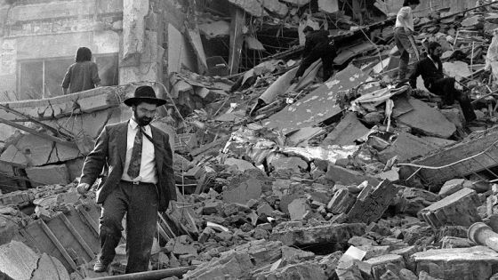 BUENOS AIRES, ARGENTINA: A man walks over the rubble left after a bomb exploded at the Argentinian Israeli Mutual Association (AMIA in Spanish) in Buenos Aires, 18 July 1994. As arguments for the AMIA trail begin, 13 January 2004, the Active Memory association, formed by the victims' relatives of the 1994 attack, will hold the Argentine government responsible for it and also seek life imprisonment for just one of the accused - Carlos Telleldin. AFP PHOTO/ALI BURAFI (Photo credit should read ALI BURAFI/AFP via Getty Images)