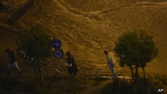 People walk next to floodwaters blocking the road due to the heavy rain in Basaksehir district of Istanbul, Turkey, Tuesday, Sept. 5, 2023. Flash floods triggered by heavy rains swept through a campsite in northwest Turkey on Tuesday, killing at least two people, officials said. Four other people were reported missing. (AP Photo/Khalil Hamra)