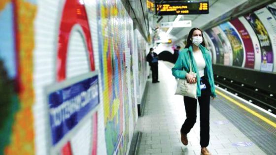 امرأة تضع كمامة طبية في محطة لقطارات الأنفاق في بريطانيا