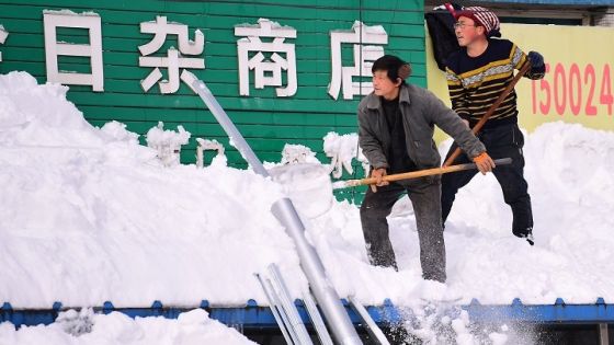 Men clear snow from a roof following heavy snowfall in Shenyang, Liaoning province, China November 9, 2021. Picture taken November 9, 2021. China Daily via REUTERS