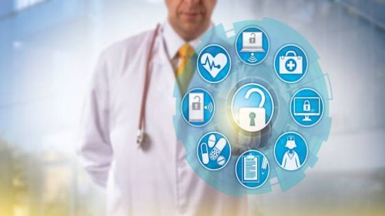 Unrecognizable doctor of medicine is accessing online healthcare data via a touch screen interface. Cyber security and IT concept for health information exchange or HIE within the medical sector.
